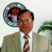 Mir N. Islam standing in front o the FSU Seal