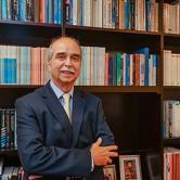 Carlos Ricardo Langoni in front of book shelf