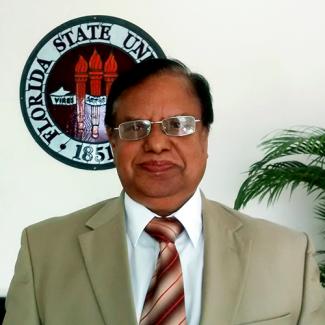 Mir N. Islam standing in front o the FSU Seal