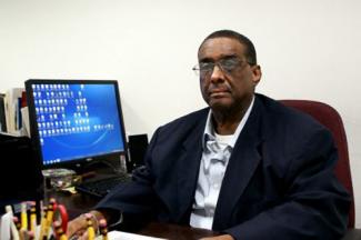Raymond George in his office sitting in front of his computer